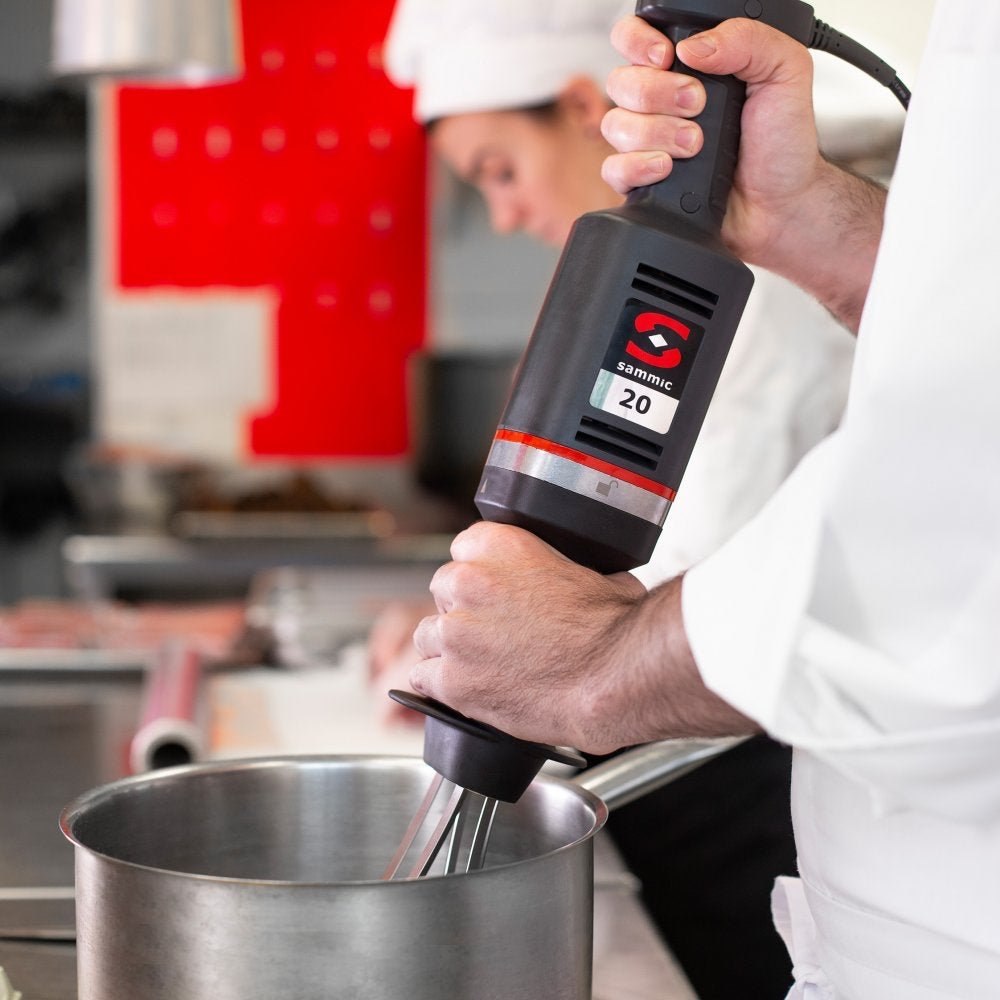 Chef utilizando el batidor de mano profesional Sammic B-20 con accesorio de varillas batidoras, ideal para montar nata, batir huevos y mezclar ingredientes en una cocina industrial.