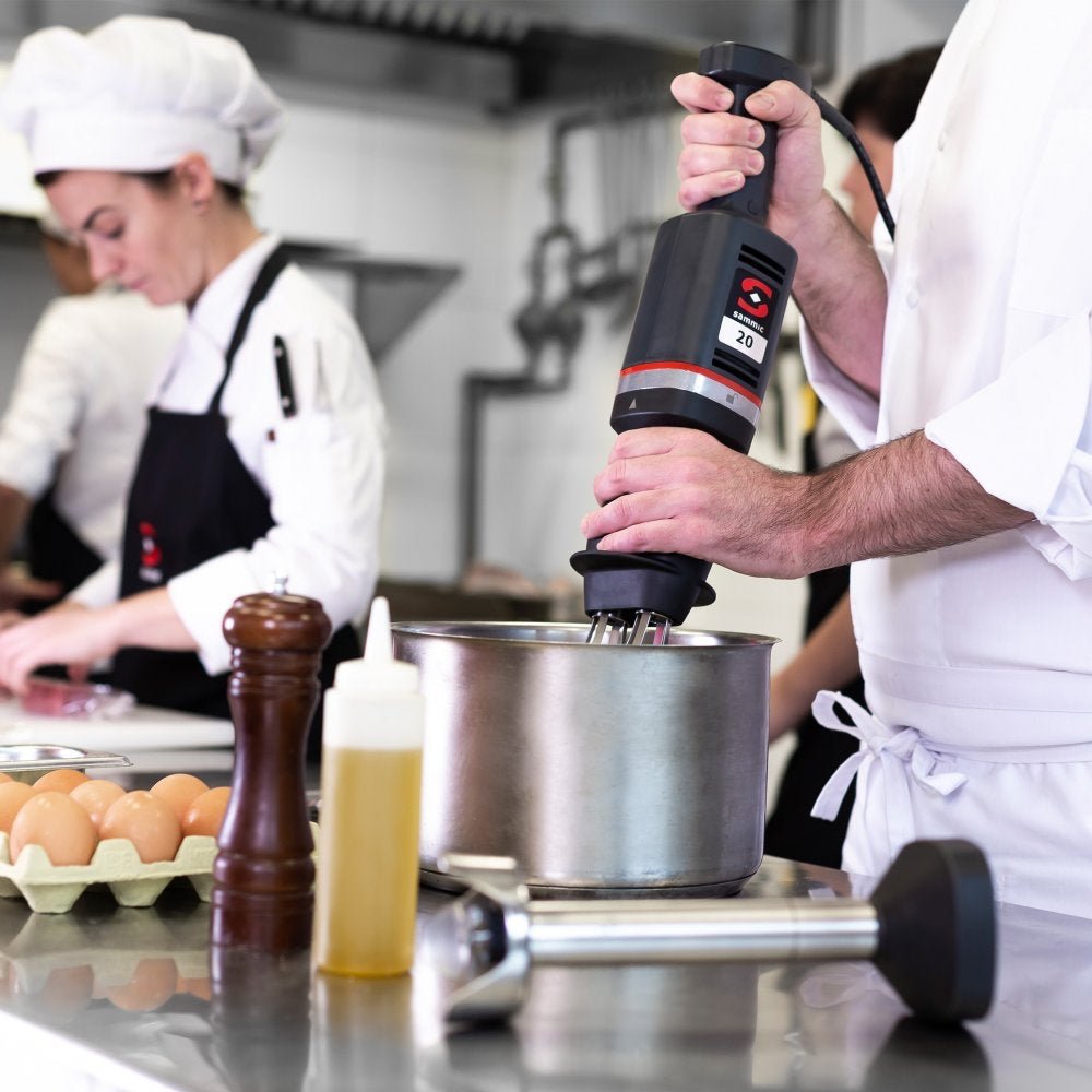 Chef utilizando el batidor de mano profesional Sammic MB-21 en una cocina industrial, ideal para preparar mezclas y emulsiones de alta calidad.