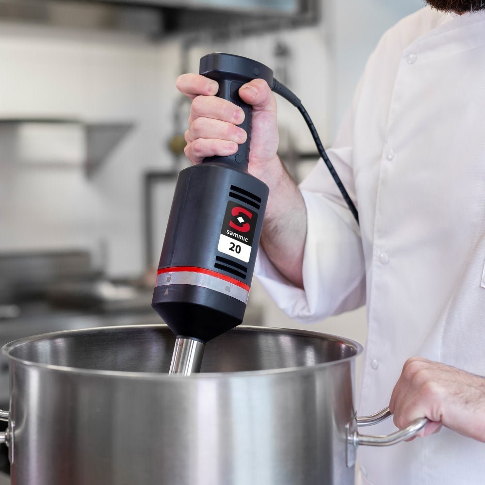 Chef utilizando el batidor de mano profesional Sammic XM-21 en una cocina industrial, ideal para mezclar y emulsionar grandes volúmenes con facilidad.