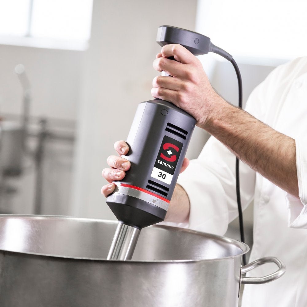 Chef utilizando el batidor de mano profesional Sammic XM-32 en una cocina industrial, ideal para procesar grandes volúmenes de alimentos con precisión y potencia